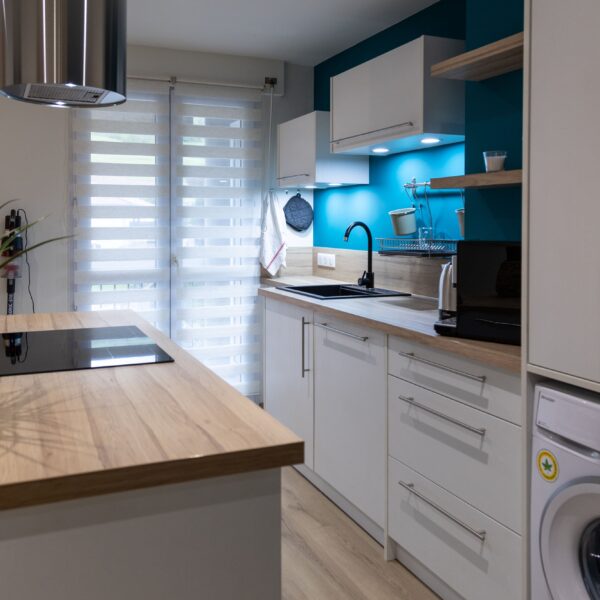 Cuisine équipée moderne appartement meublé Aurillac - Plan de travail, électroménager et lave-linge aux Jardins du Pont Rouge